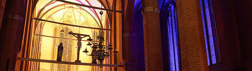 Das innere der Unikirche, erleuchtet von Kerzenschein und lila Licht durch die Fenster von außen.