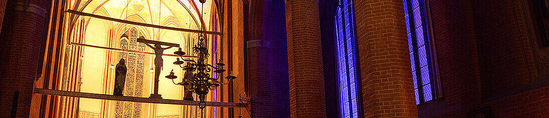 Das innere der Unikirche, erleuchtet von Kerzenschein und lila Licht durch die Fenster von außen.
