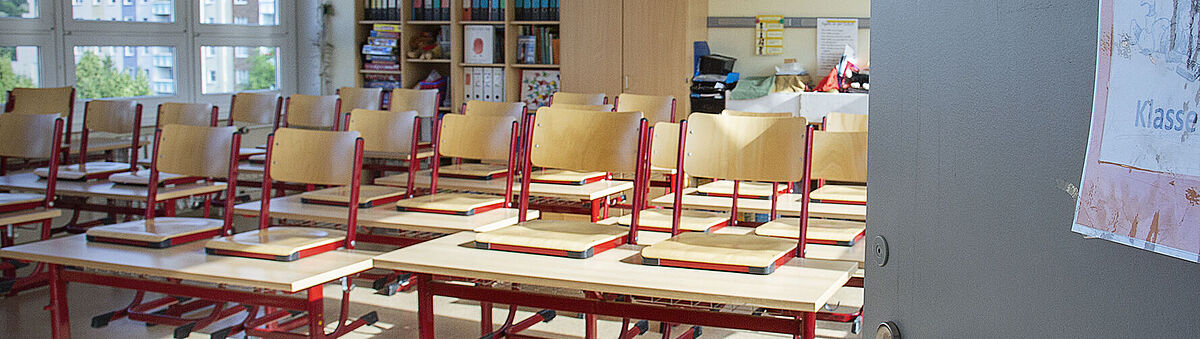 Eine offene Tür lässt in ein Klassenzimmer blicken.