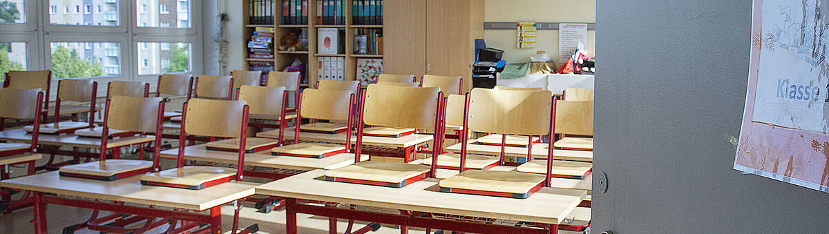 Eine offene Tür lässt in ein Klassenzimmer blicken.