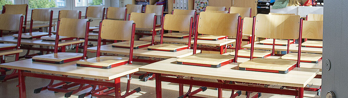 Eine offene Tür lässt in ein Klassenzimmer blicken.