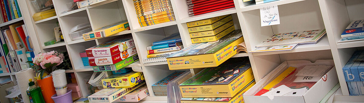 Viele Schulbücher liegen in einem Regal.